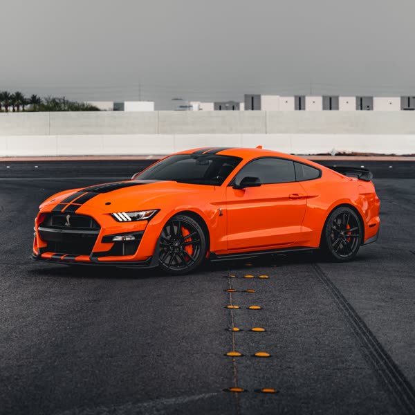 Orange Shelby GT500 with black stripes outside the shop